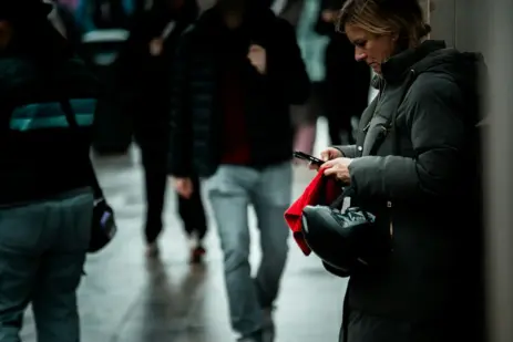 Kvinde ser på telefon i byens regn som illustration af moderne dating og dating burnout