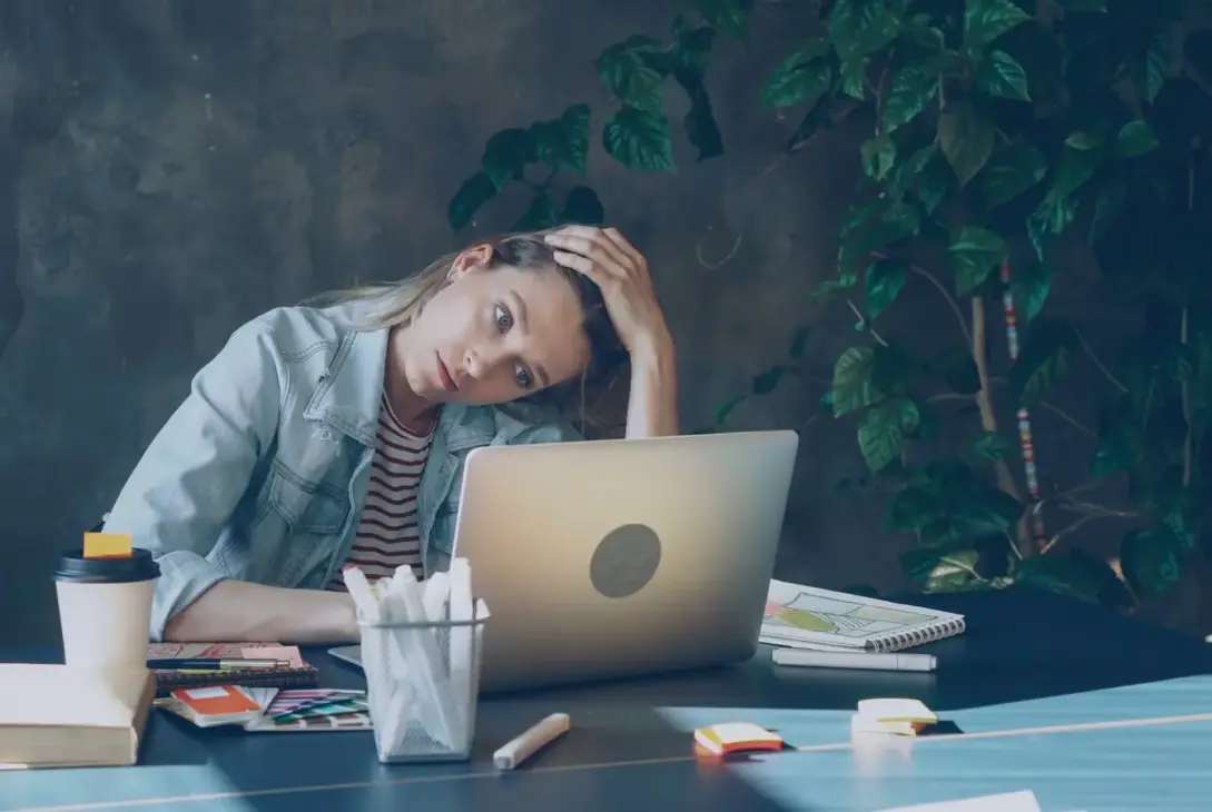 Kvinde foran laptop i moderne kontor som illustration af stress i arbejdslivet og LinkedIn-kultur