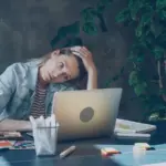 Kvinde foran laptop i moderne kontor som illustration af stress i arbejdslivet og LinkedIn-kultur