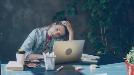 Kvinde foran laptop i moderne kontor som illustration af stress i arbejdslivet og LinkedIn-kultur