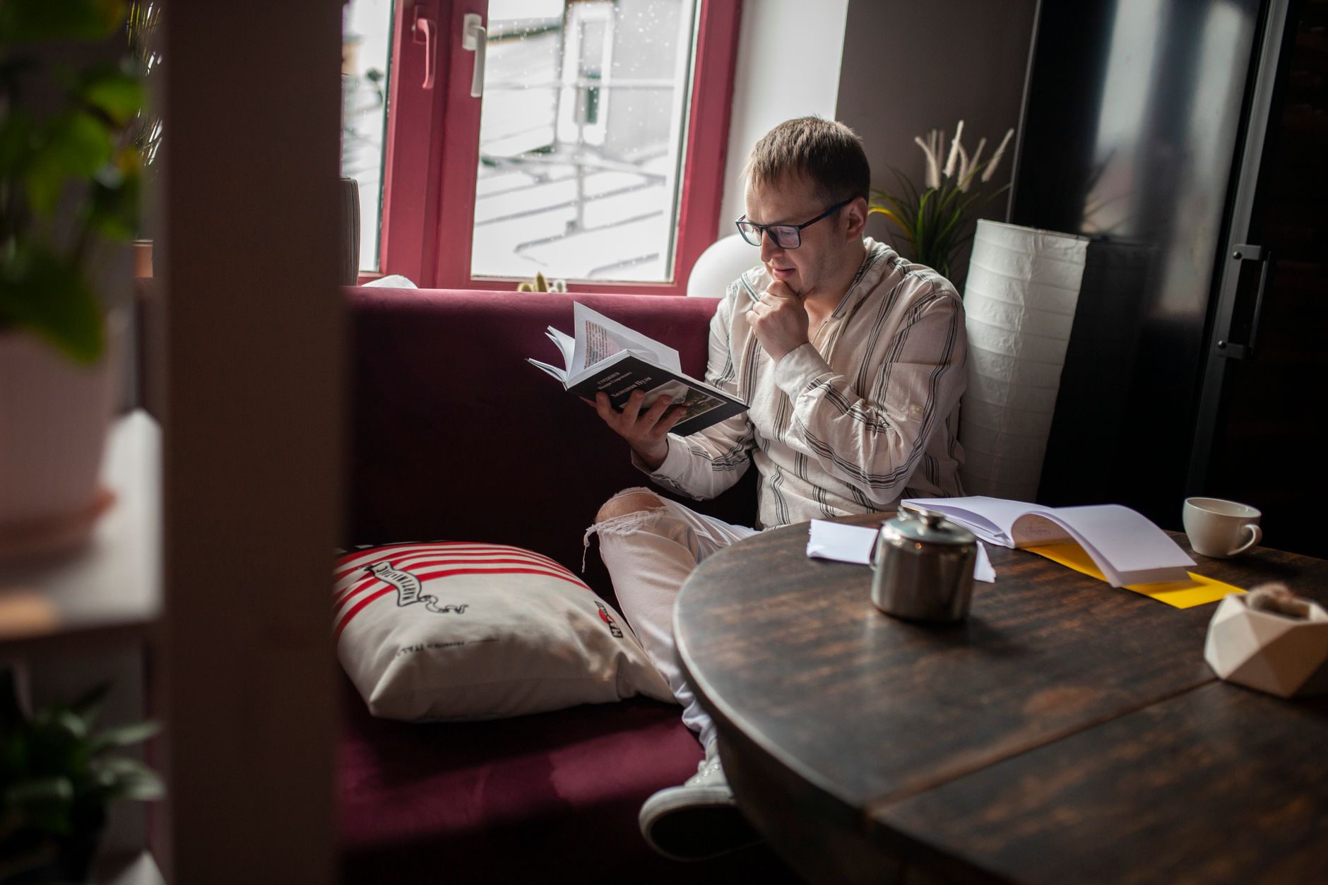 Person hviler med en bog i sofaen i blødt dagslys